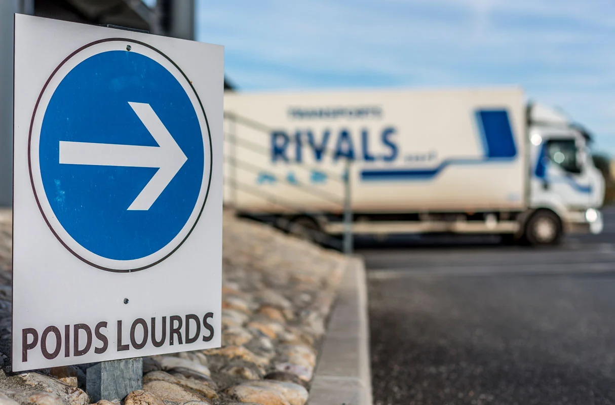 Parking transport Rivals avec un panneau qui indique la direction des poids lourds