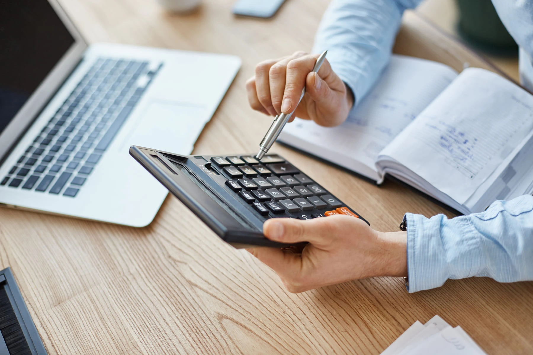 Personne en train de réaliser un devis à l'aide d'une calculatrice